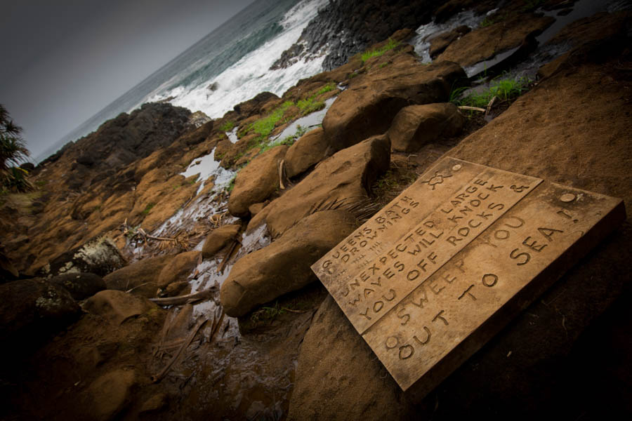A hand-lettered warning board on the rock, swept off rocks and out to sea, Kauai
