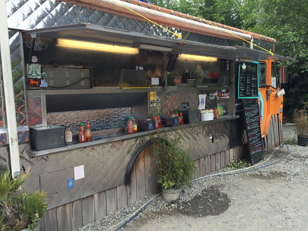 The open-air counter of a Tofino food cantina, boards chalked up above the hatch, Tofino